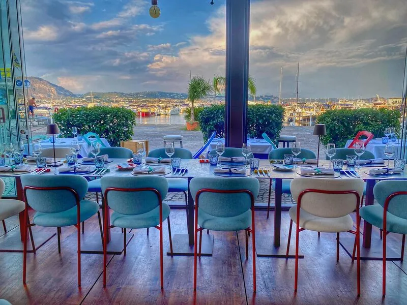Sala di Riccio Restaurant con tavola apparecchiata e vista sul porto di Baia