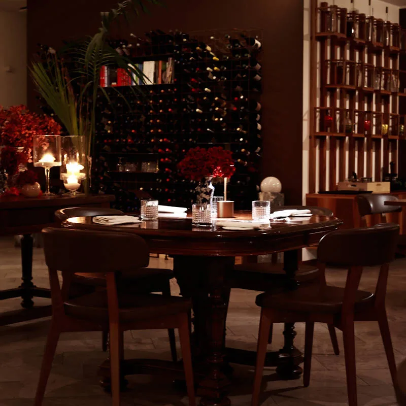 Tavolo rotondo apparecchiato nella sala de Il Principe, con candele, fiori e bottiglie di vino sullo sfondo