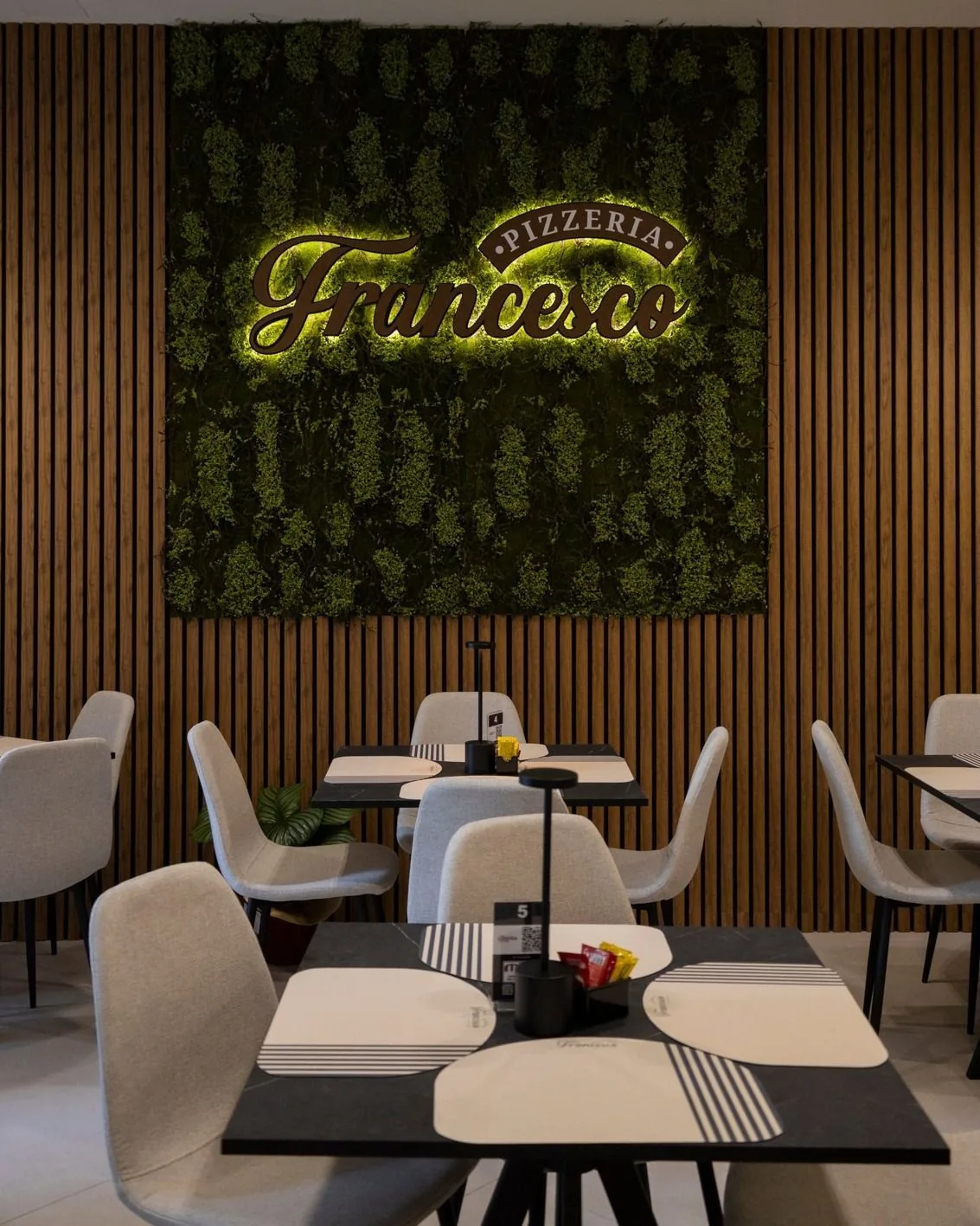 Sala di Pizzeria Da Francesco con il logo del locale sulla parete verde
