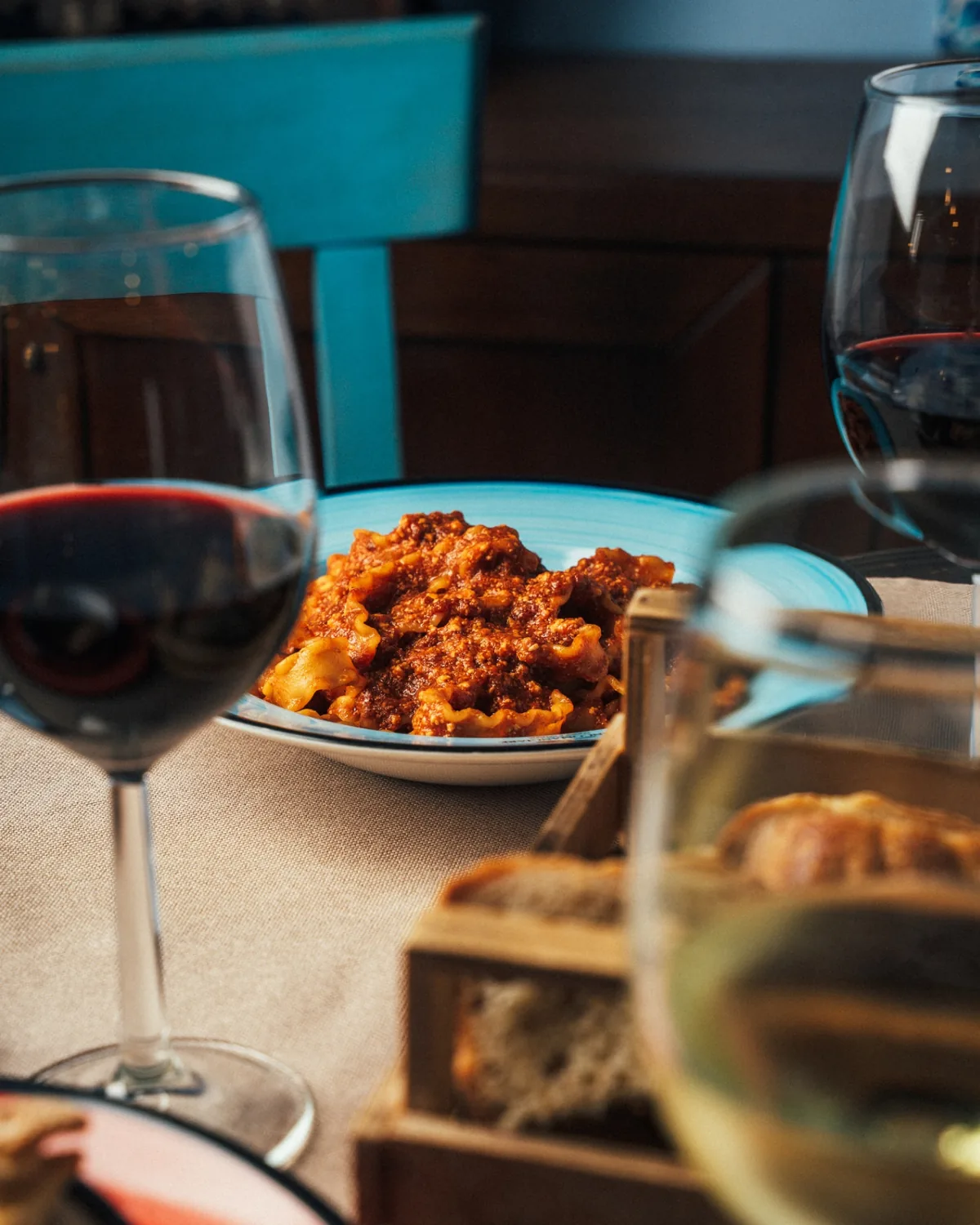 Pasta al ragù napoletano servita a tavola con calici di vino