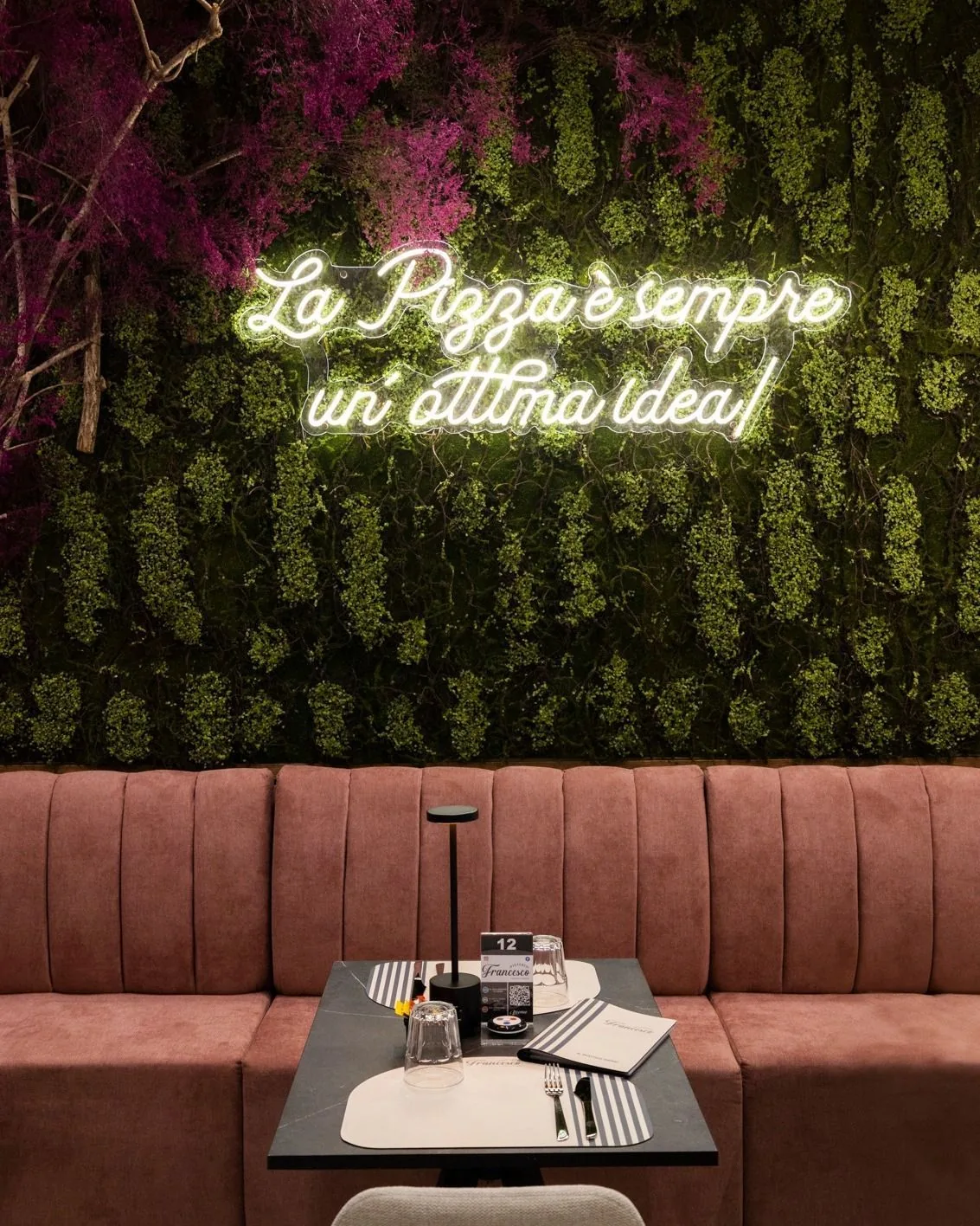 Angolo della sala di Pizzeria Da Francesco con parete verde e insegna luminosa
