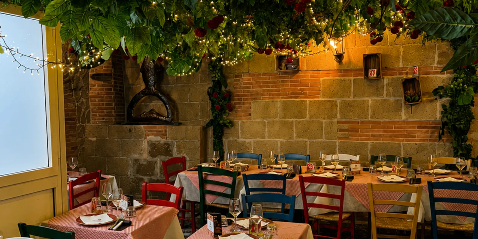 Sala interna della Locanda del Monacone con tavoli colorati e pergolato di luci
