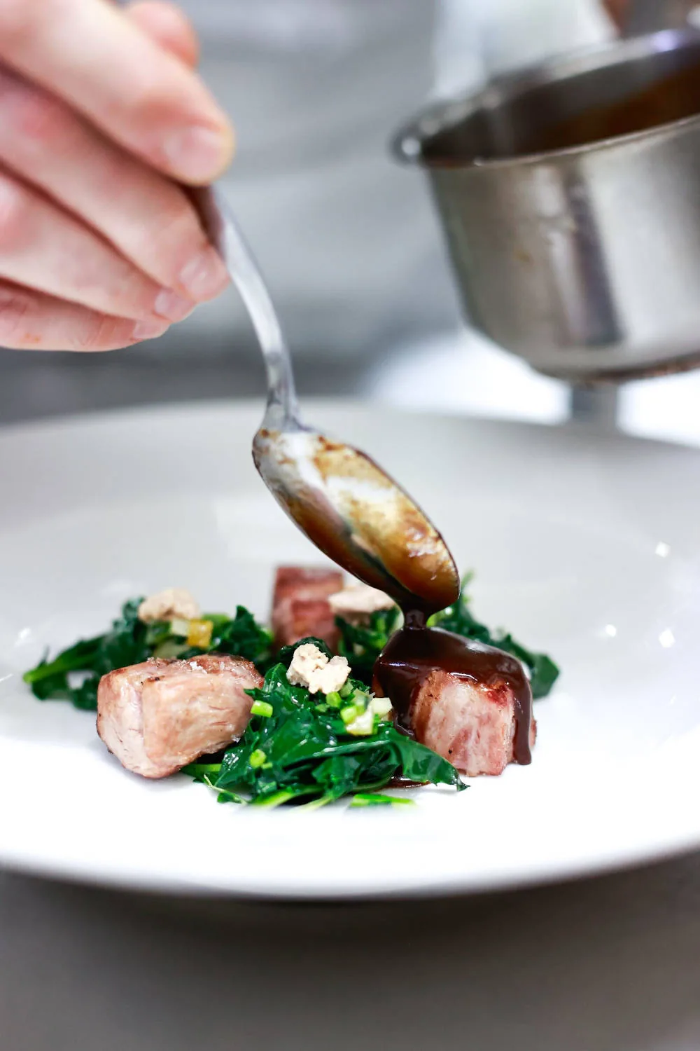 Preparazione di un piatto de Il Principe: la salsa viene versata sulla carne accompagnata da verdure